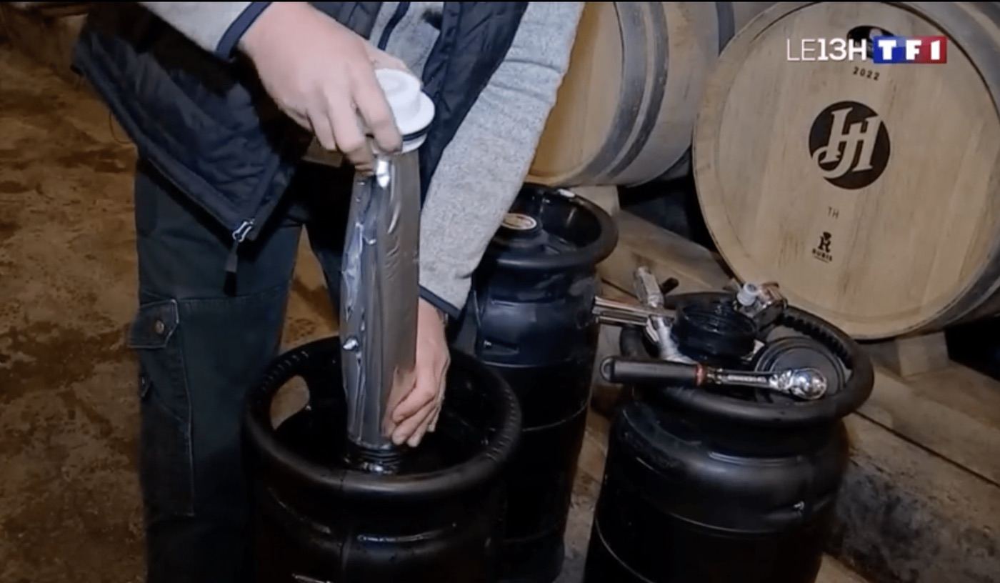 Still from TF1's 1 pm news: a wine liner being inserted into an ECOFASS keg, in a cellar